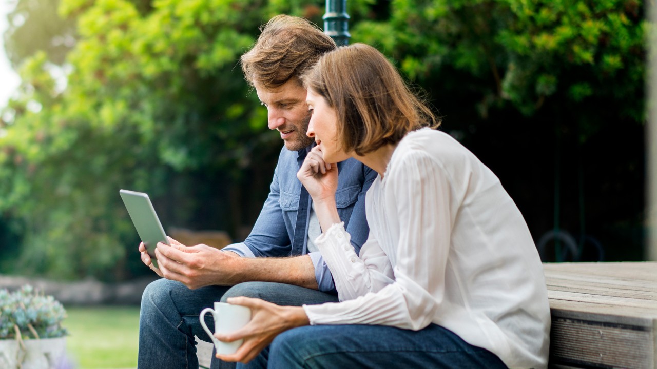 Couple browsing on tablet in the park