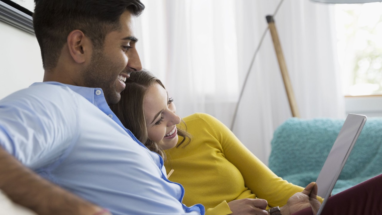 couple hugging checking laptop